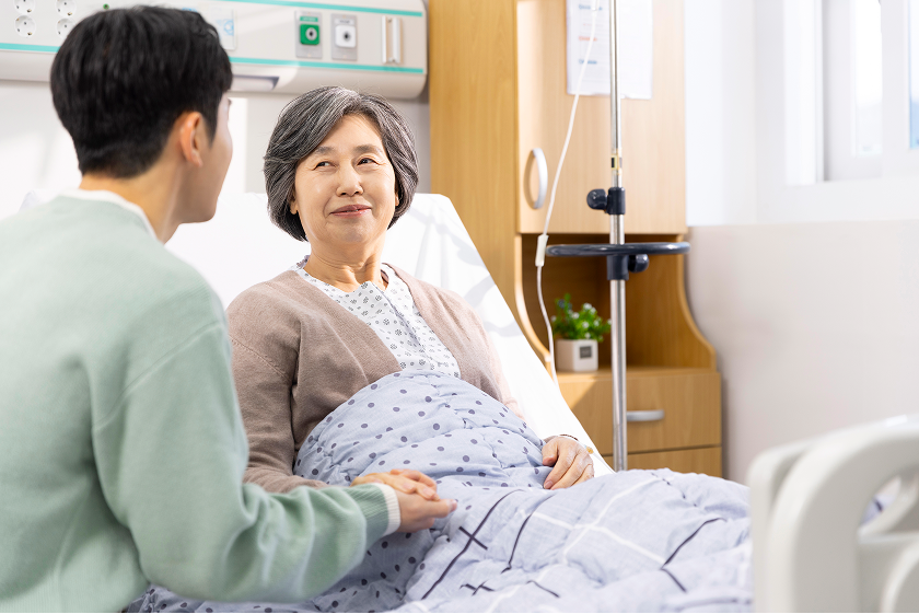 병원 병상에서 노인 환자를 돌보는 보호자와 간병 서비스 상담 모습
